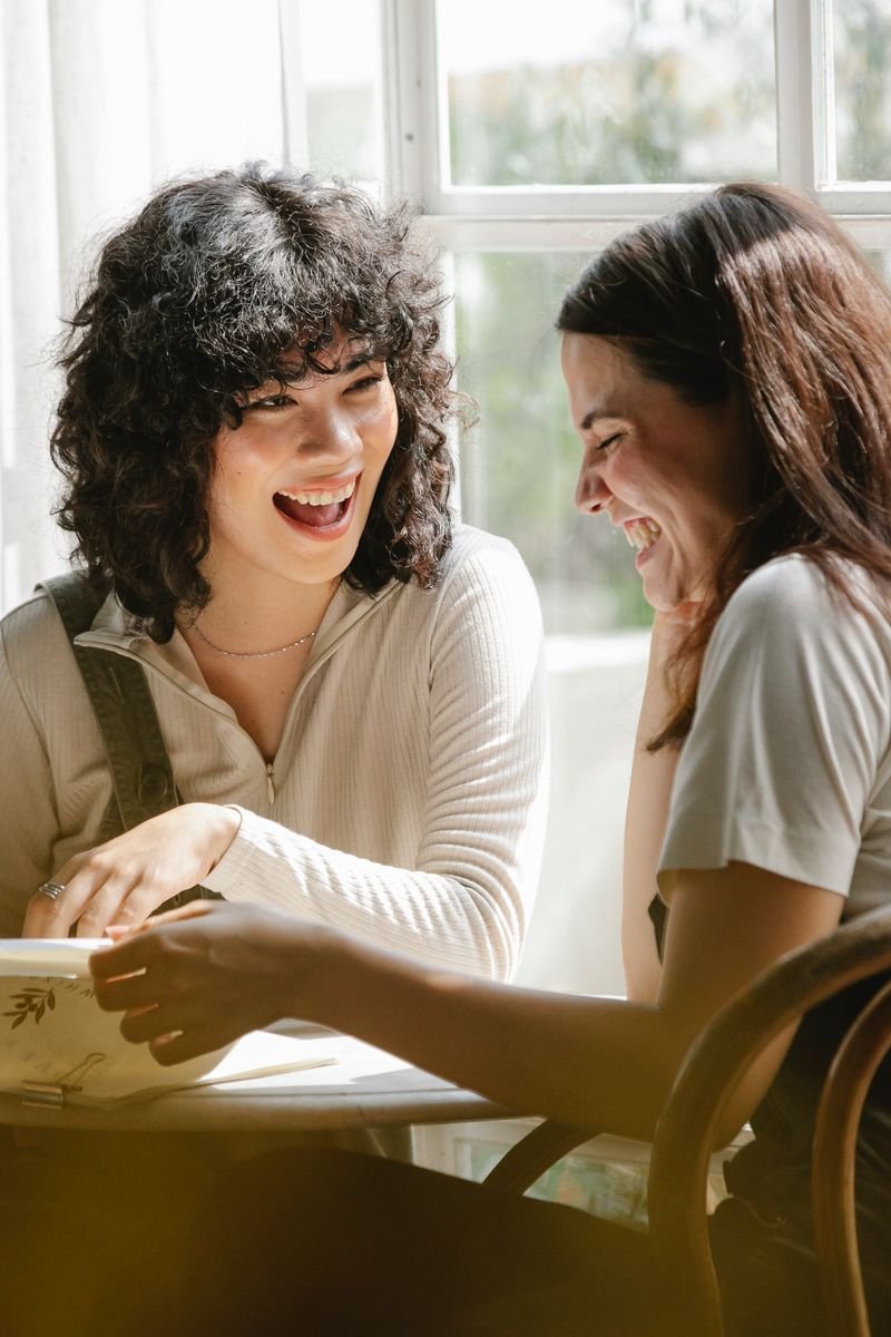 Laughing multiracial female colleagues wearing uniform flipping pages of papers while discussing work together